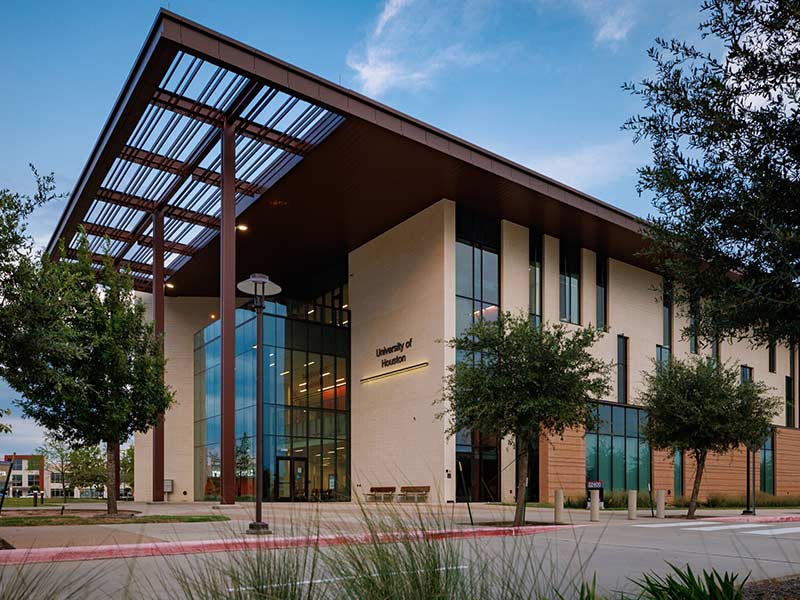 Front of a brick and glass building with a sign that says, "University of Houston"